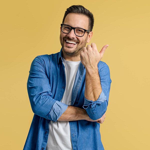 Smiling man pointing yellow background